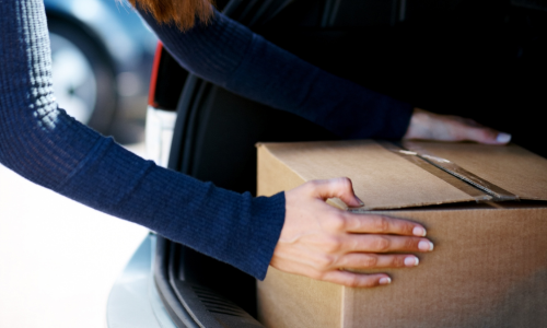 Woman putting a box into a trunk of a car