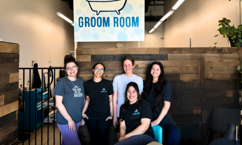 Carlsbad staff standing in the Groom Room in front of the Groom Room sign